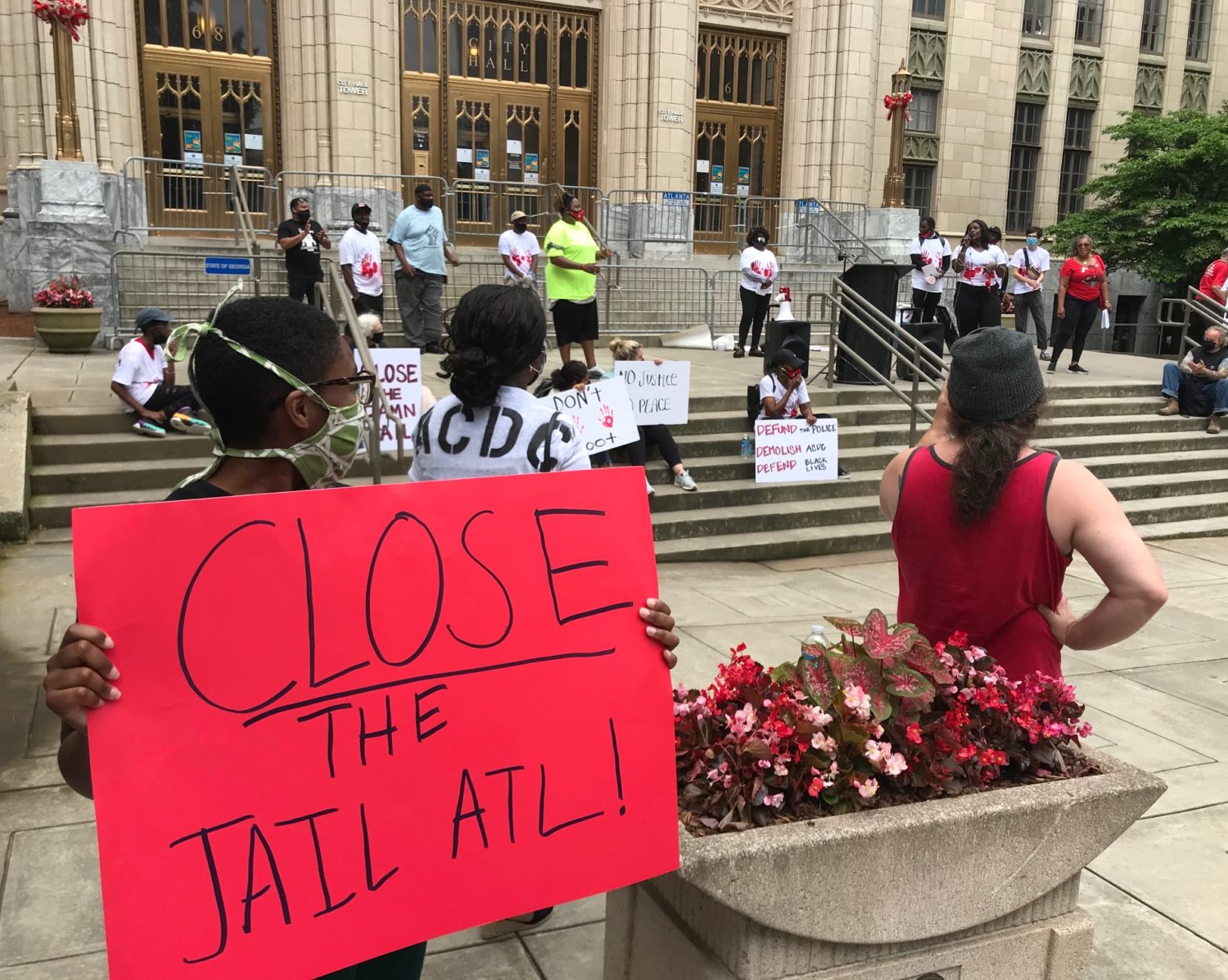 A small rally on the steps of Atlanta City Hall. A person holds a sign that says Close the ATL Jail
