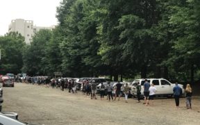 Dozens and dozens of people in a line in a parking lot